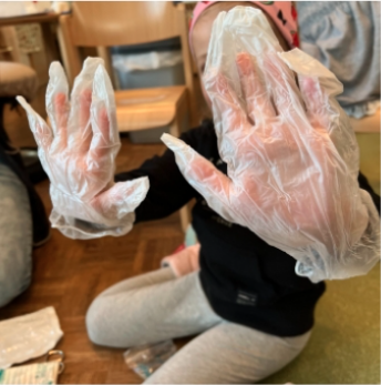 A child is proudly showing that it wears protective gloves.